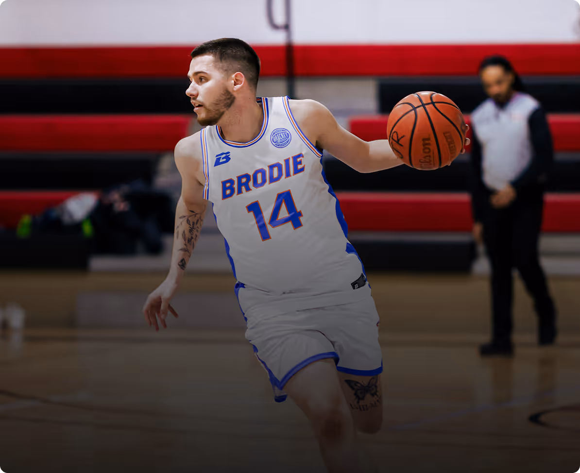 Basketball player wearing Brodie 14 jersey dribbling a basketball on indoor court.