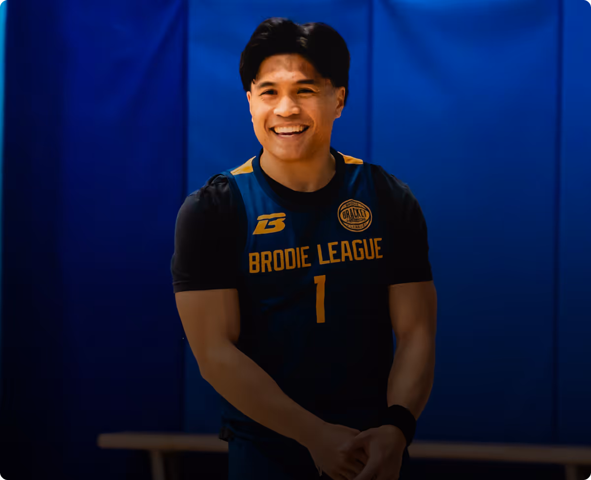 Smiling basketball player in black and blue Brodie League jersey with number 1 on a court.