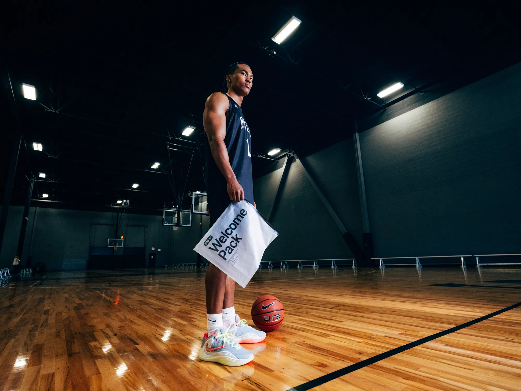 BRODIE athlete holding a Welcome Pack on a basketball court