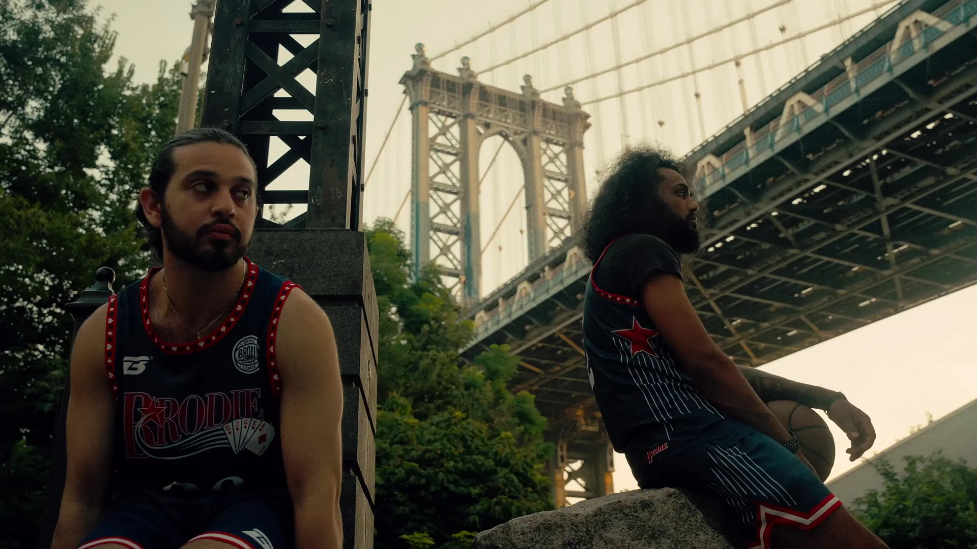 Two Brodie athletes in jerseys under the Brooklyn Bridge