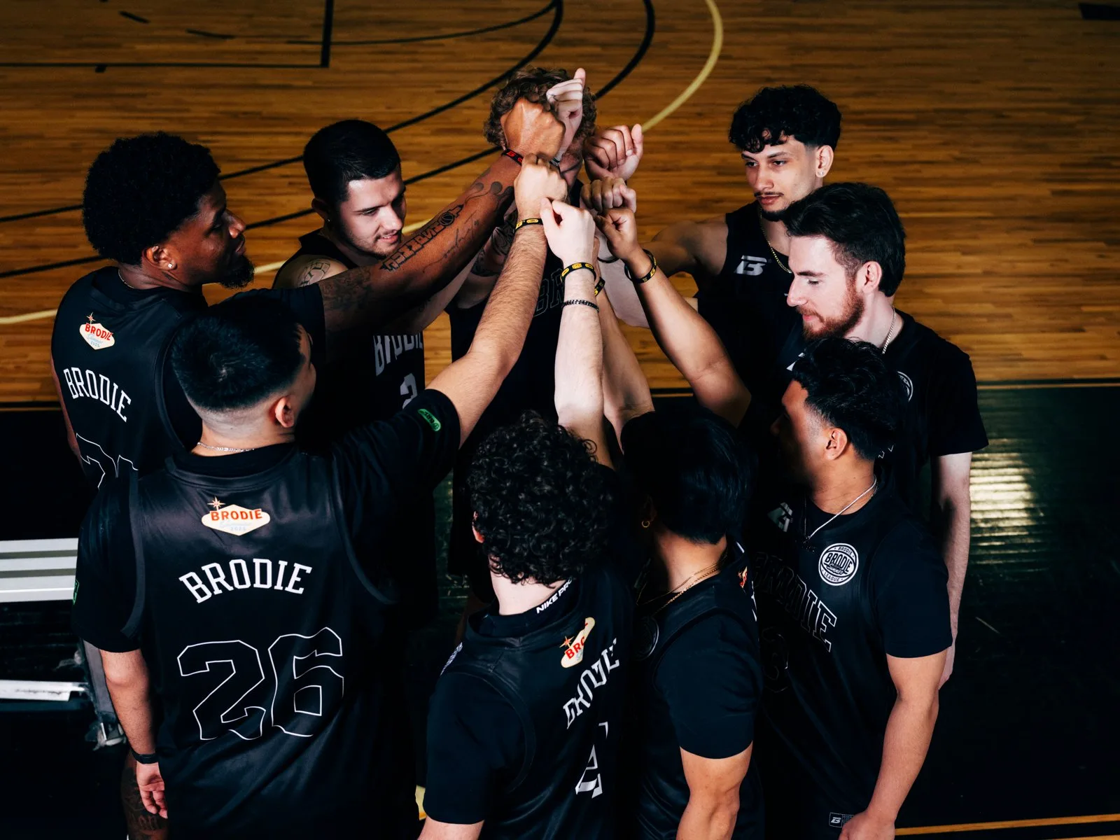 Brodie team huddled with hands in