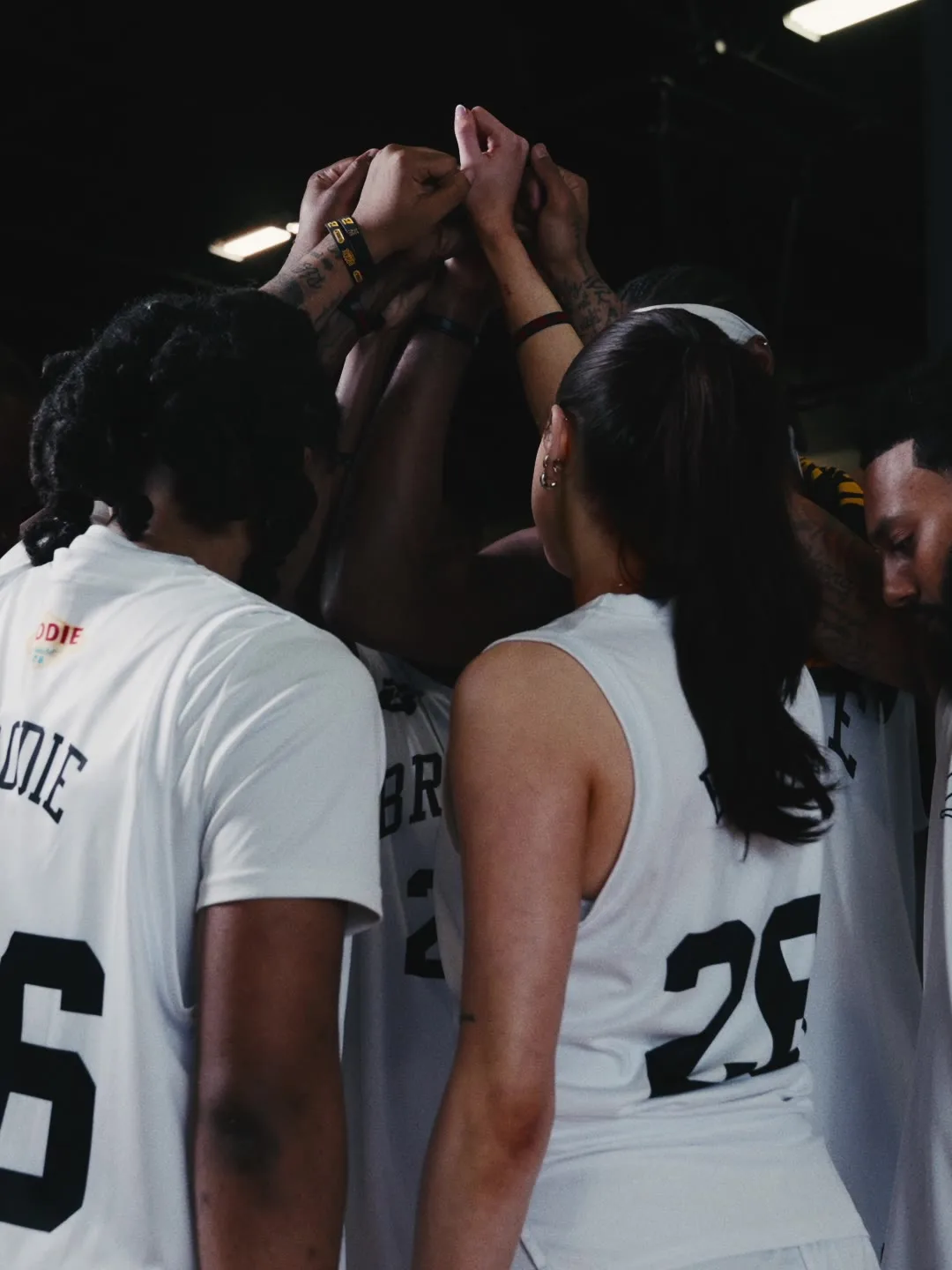 Brodie team in a huddle with hands raised