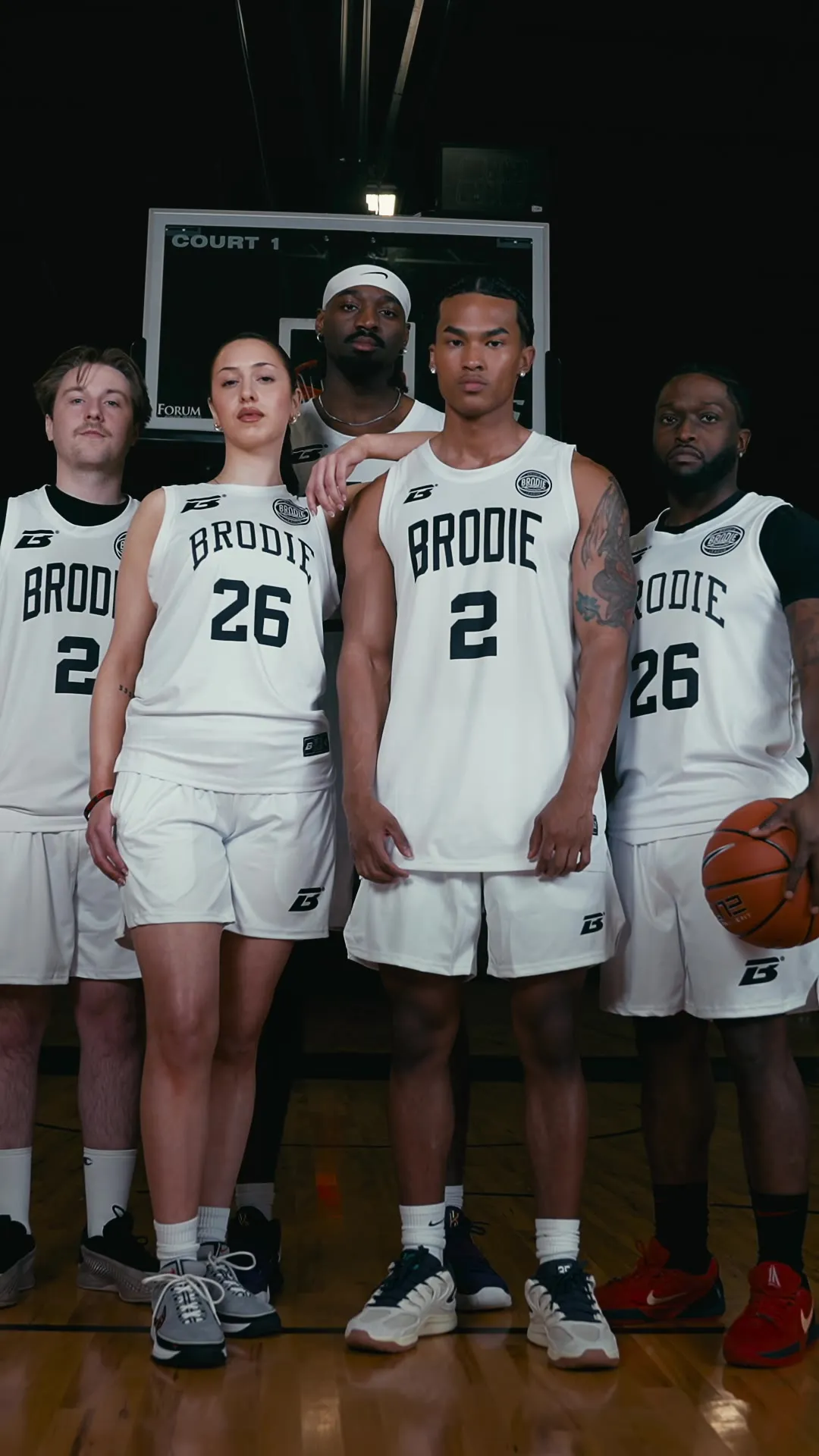 Five Brodie athletes in white jerseys standing together on court