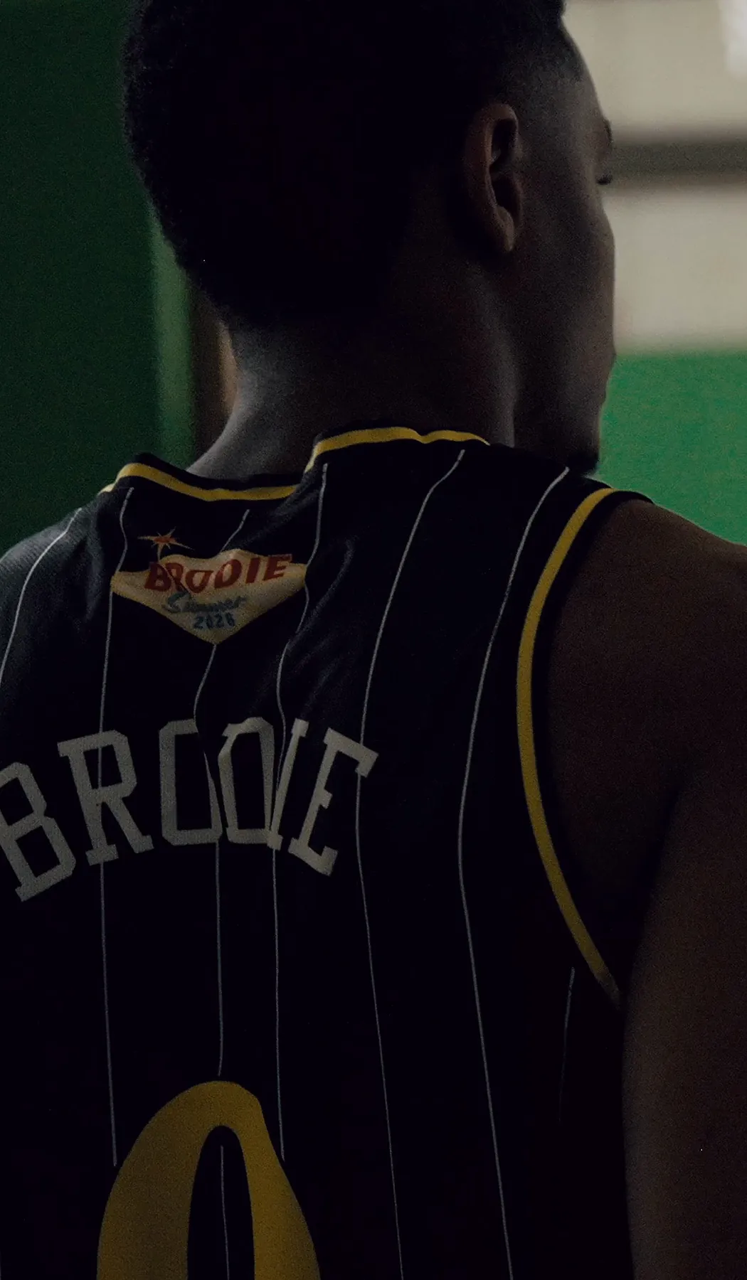 BRODIE athlete in a number 0 jersey walking onto the court, seen from behind