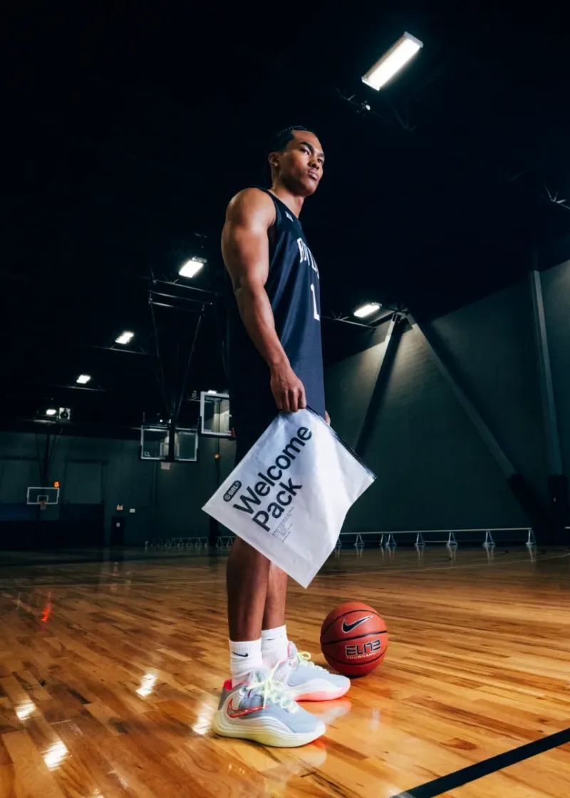 Brodie athlete holding his welcome pack on an empty court