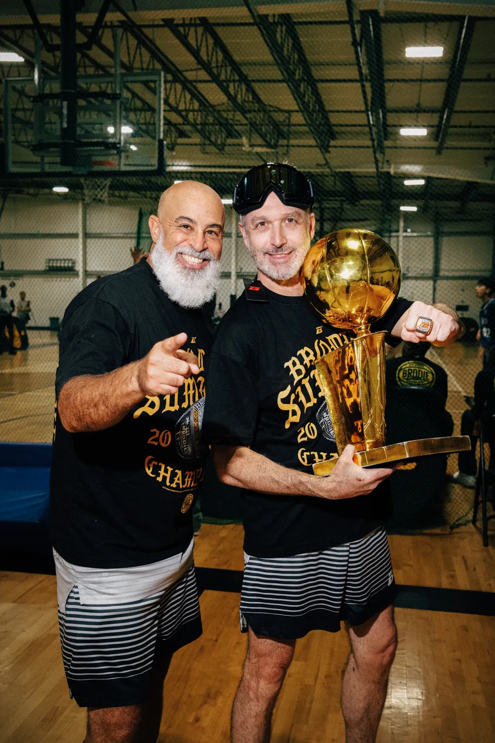 Two BRODIE champions in black shirts holding the trophy