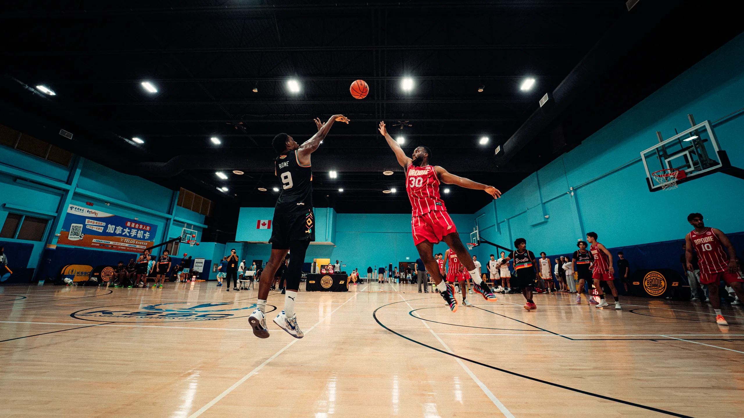 BRODIE athlete in a red jersey leaping to block a jump shot