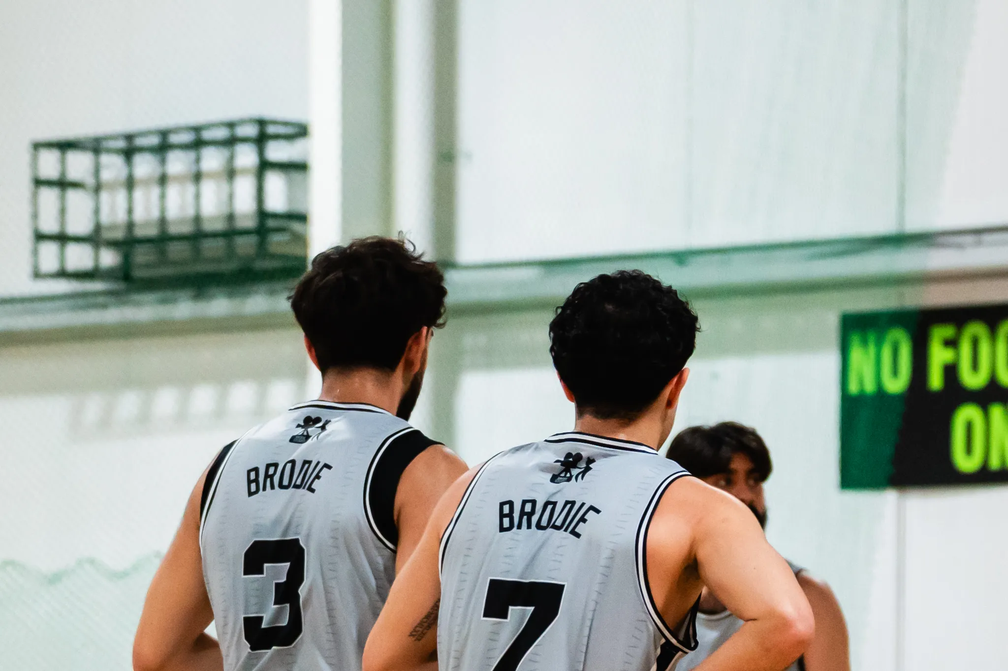 Two Brodie teammates walking onto the court arm in arm