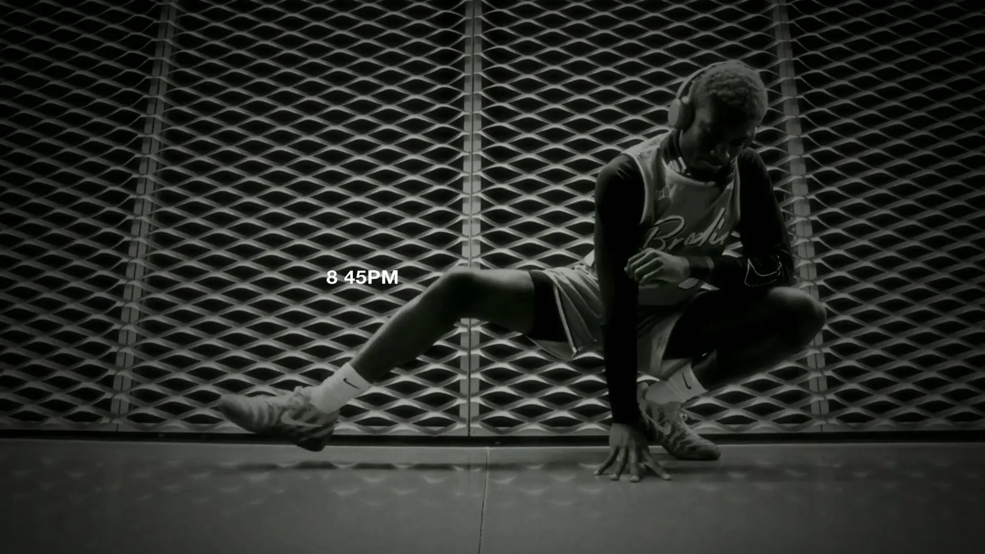 A BRODIE athlete crouched on a basketball court at 8:45PM, in black and white