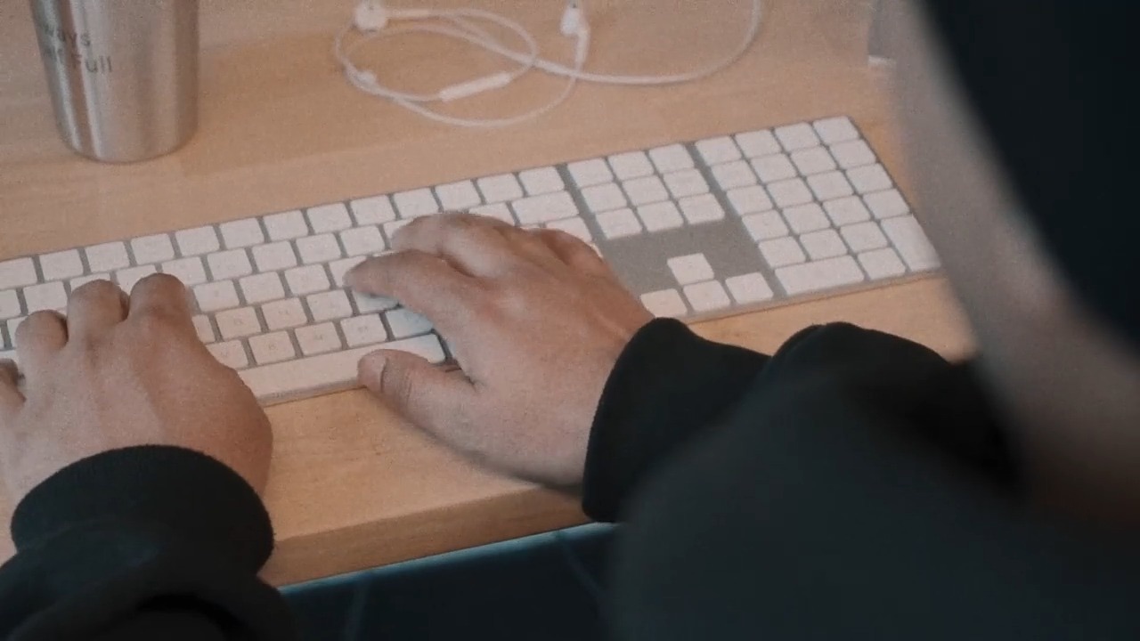 Hands typing on a keyboard at a desk
