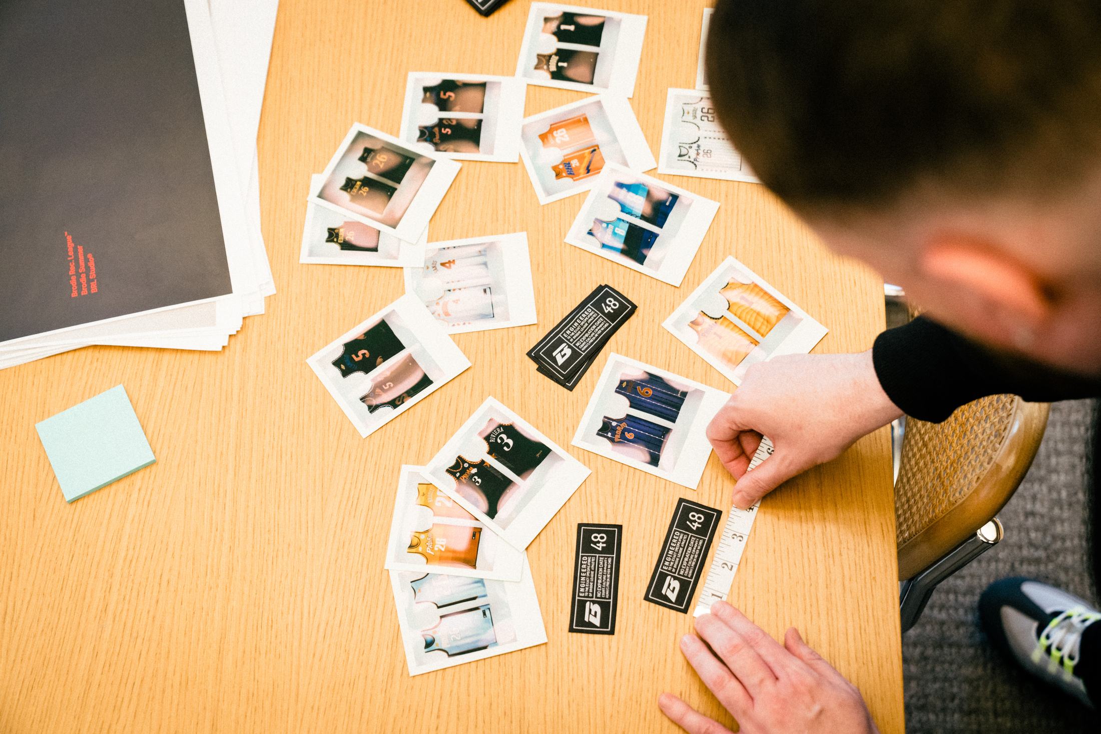 Polaroids of Brodie jerseys laid out on a desk during a planning session