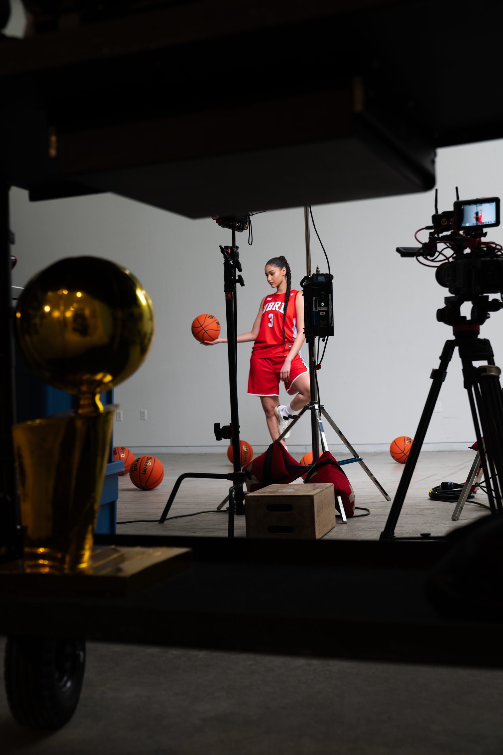 Studio shoot with a player in a red jersey, a gold trophy and cameras