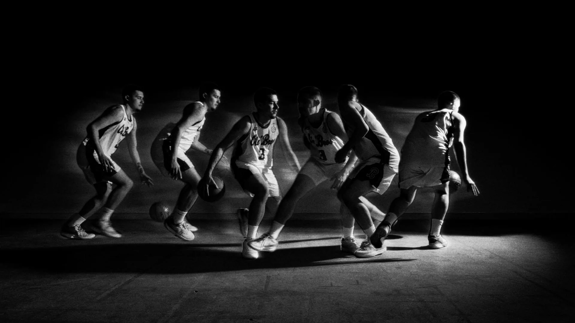 Black and white multiple exposure of a player driving through the lane