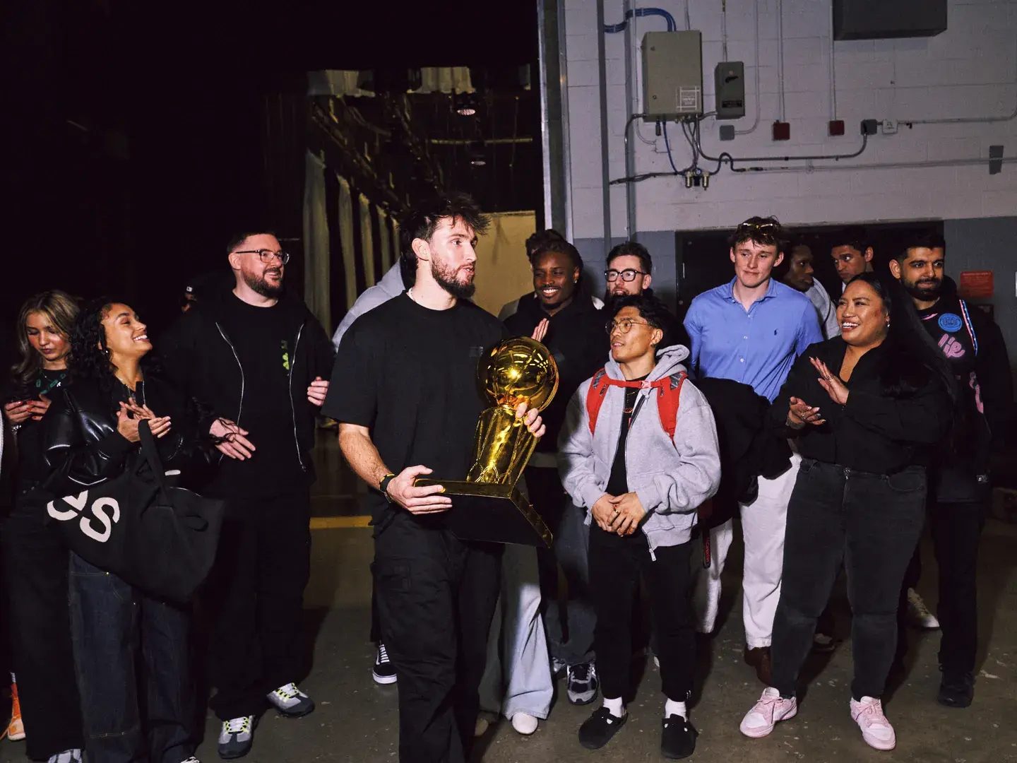 Brodie team gathered backstage, cheering a teammate holding a gold championship trophy