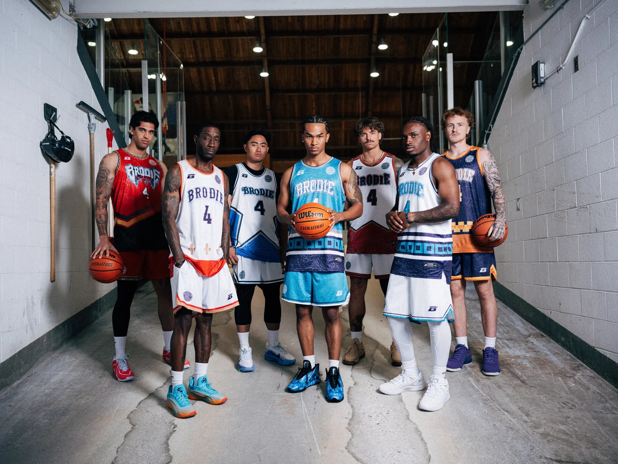 Seven athletes in different Brodie jerseys stand side by side in a tunnel