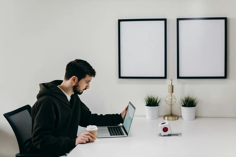 Mann mit Kaffee und Laptop am Schreibtisch