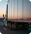 Payable Moving Company truck driving down the highway at sunset, metallic trailer reflecting the sky colors.