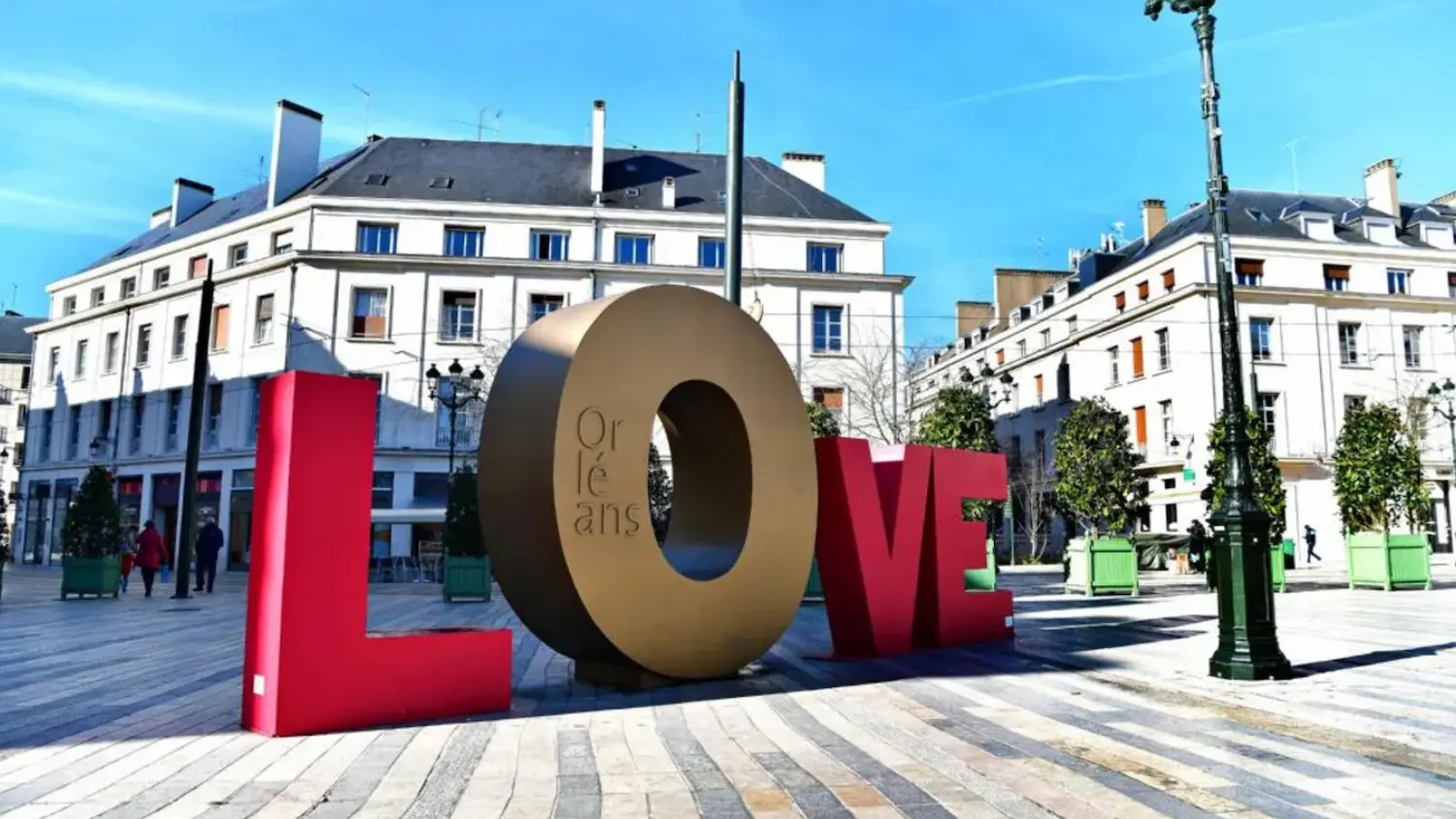 Large colorful letters spelling LOVE in a town square with buildings and trees in the background, with the 'O' inscribed with 'Orléans'.
