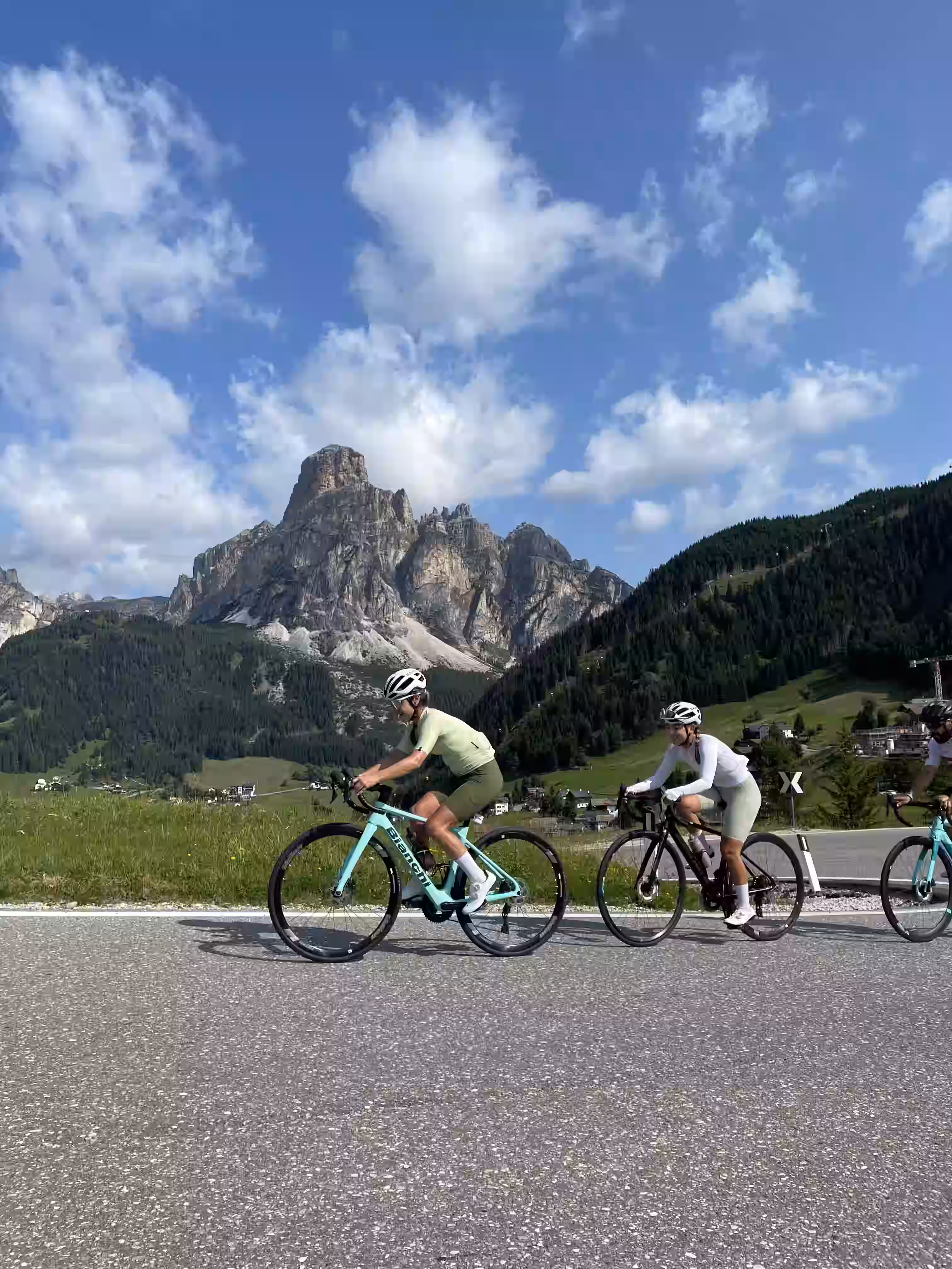 Due cicliste in abbigliamento tecnico e casco pedalano su una strada di montagna ad Arabba nelle dolomiti, durante il Sellaronda tour