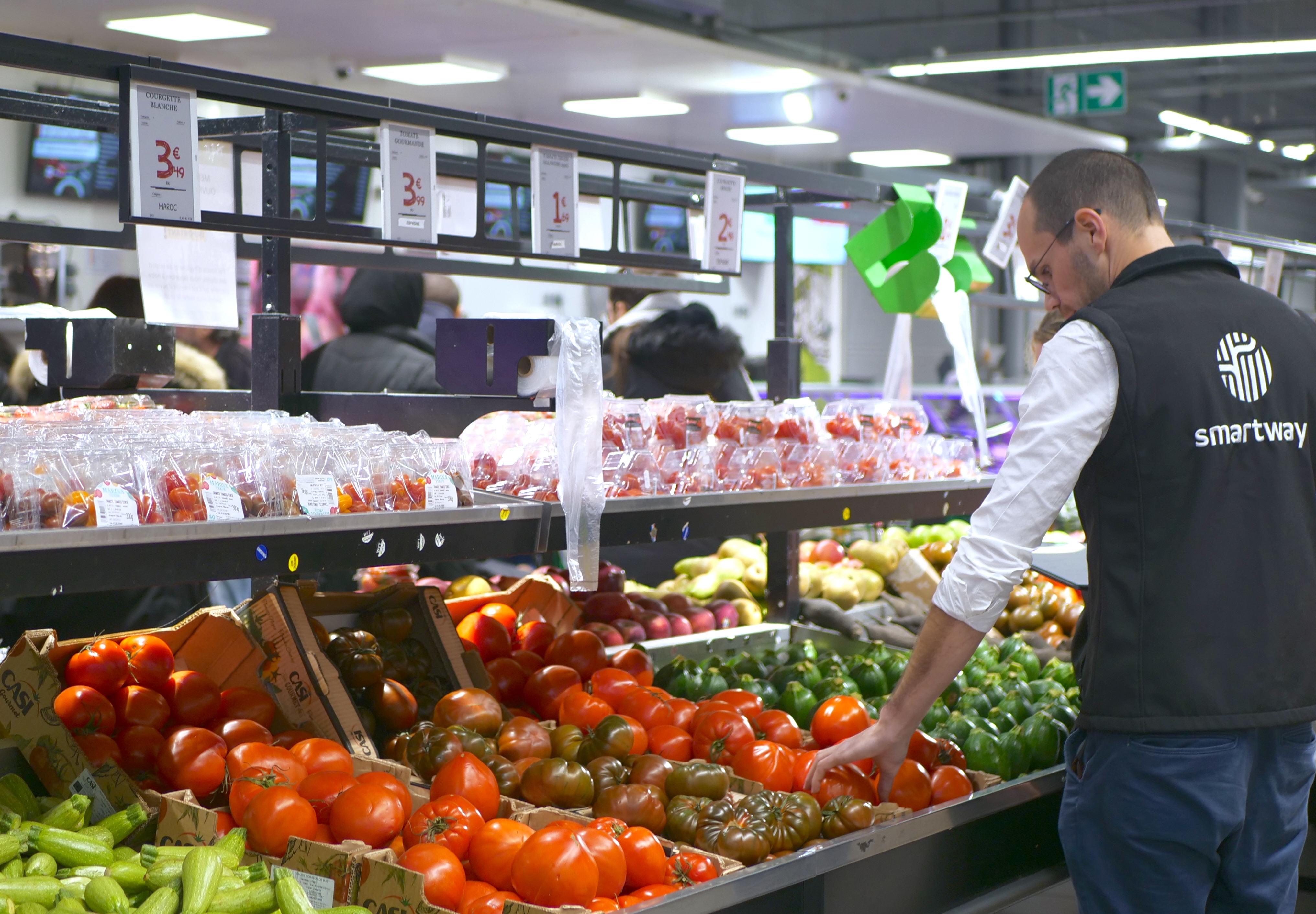 store employee in front of his produce stand checking batches