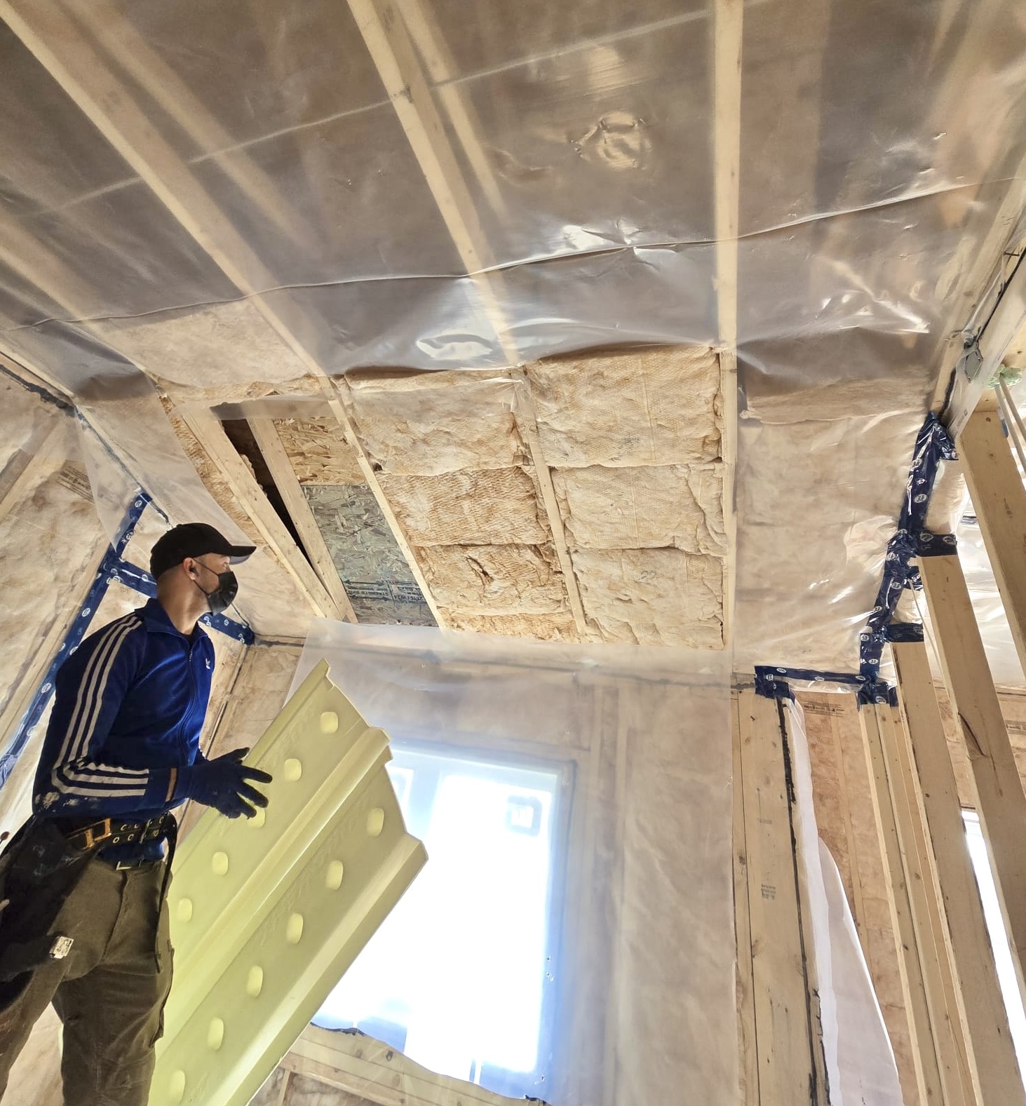 A worker installing insulation in the ceiling.