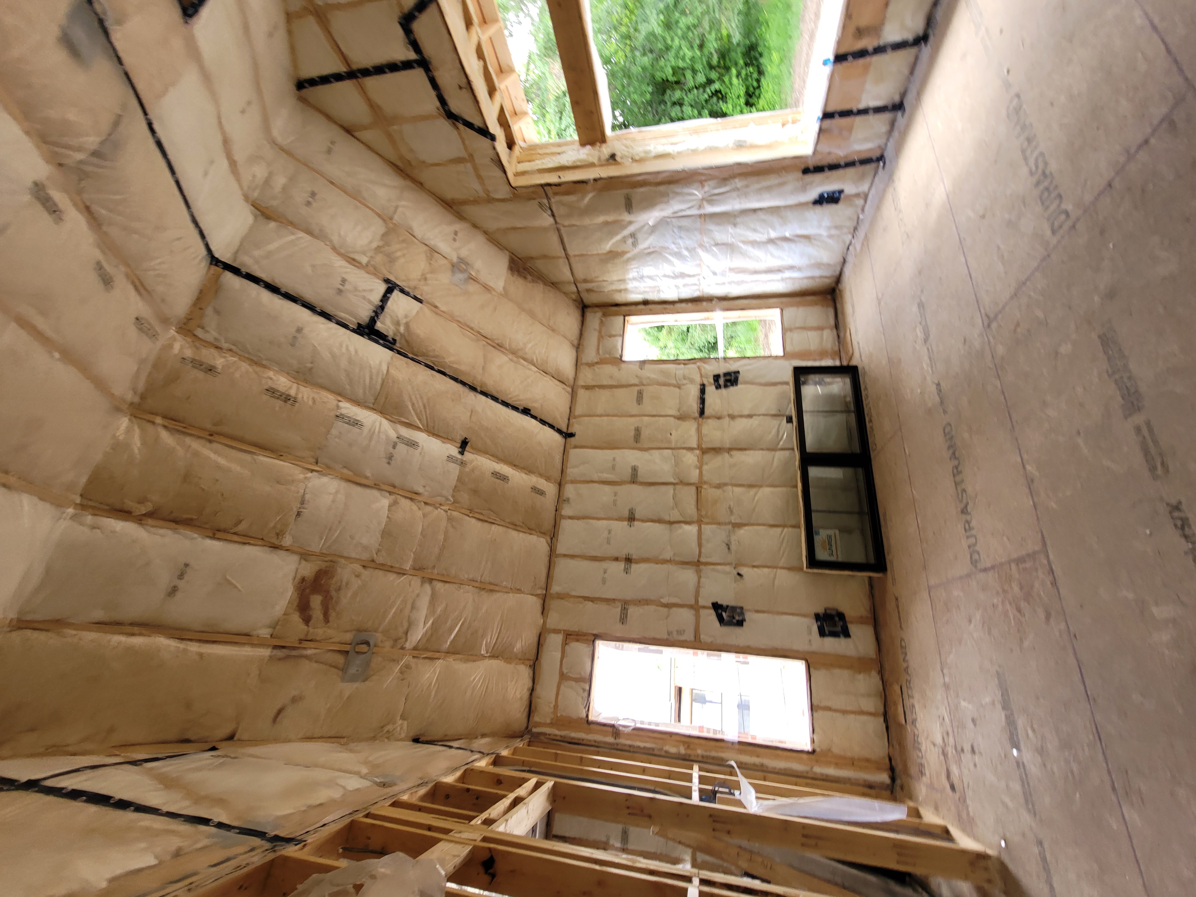 A house under construction with several windows and insulation being installed.