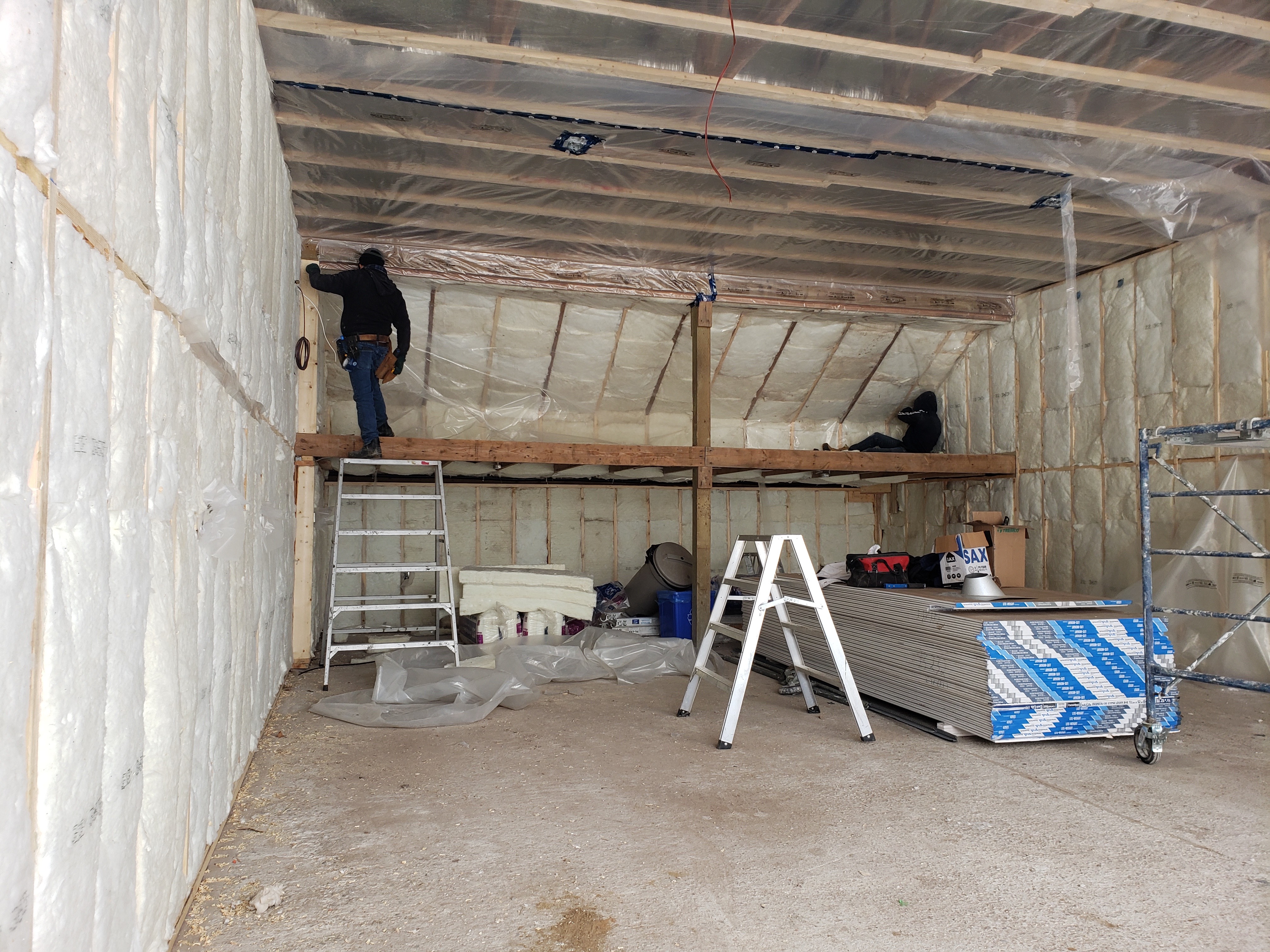 Two workers installing insulation in a garage.