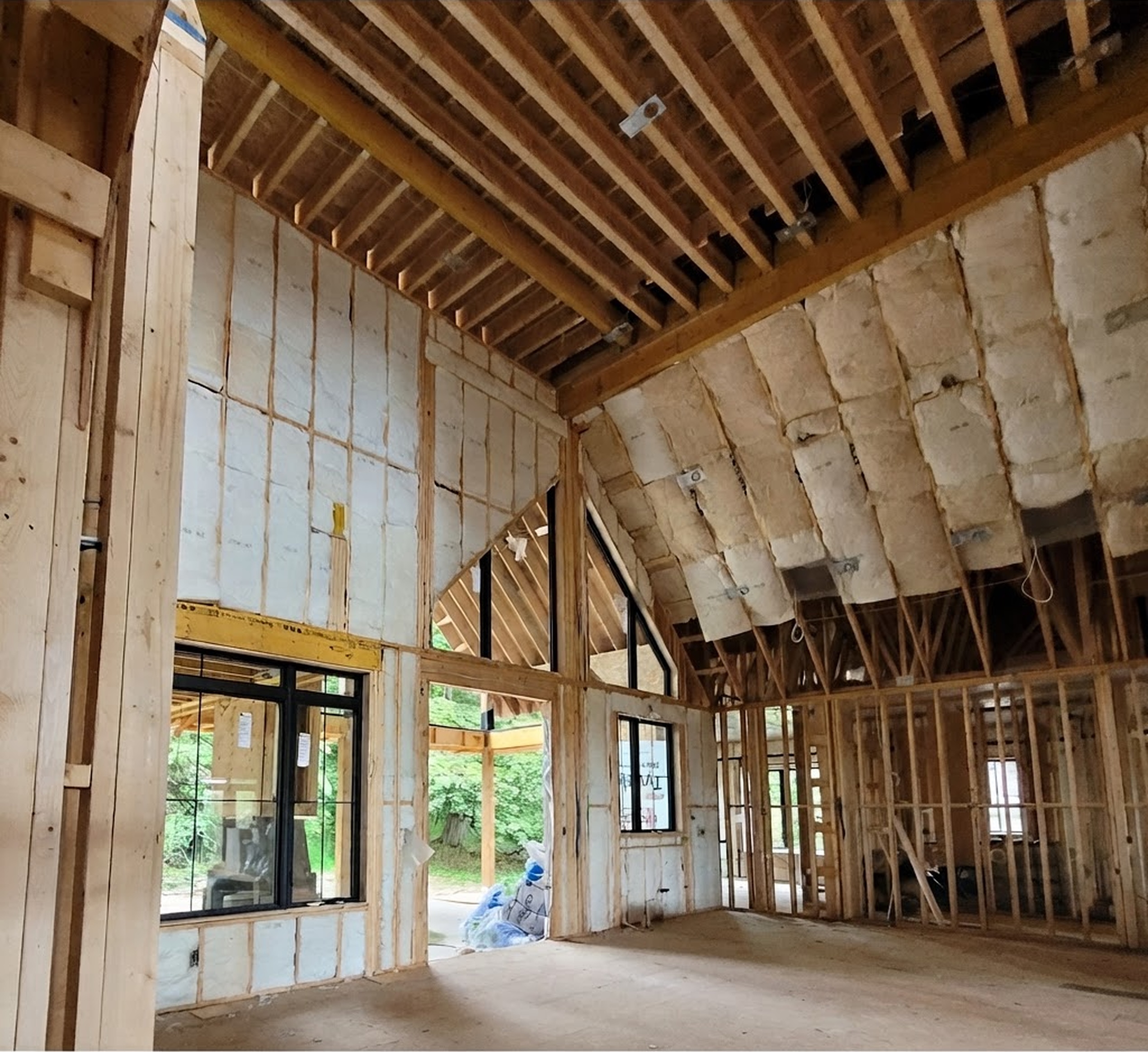 A house under construction with several windows and insulation being installed.