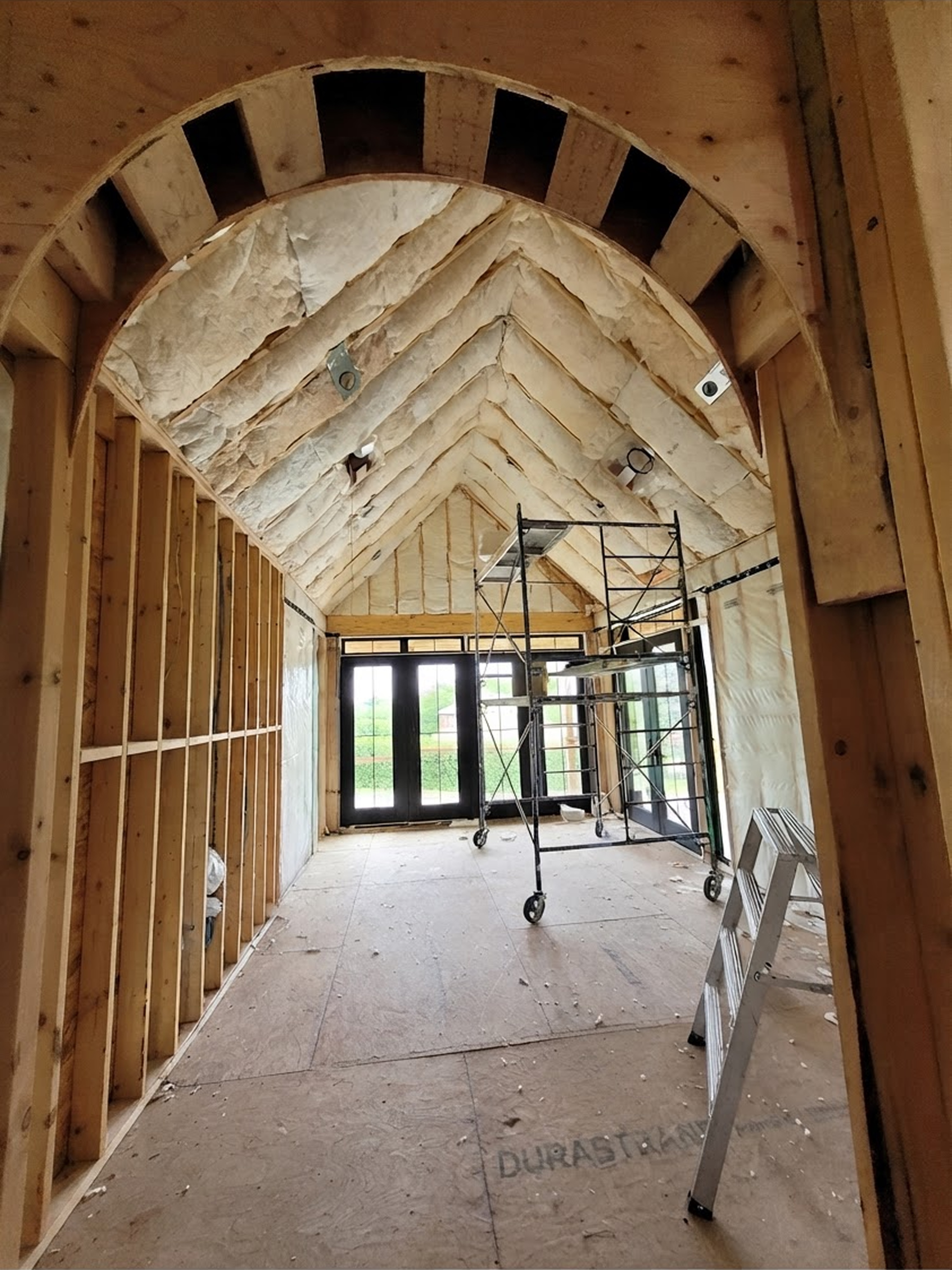 House in construction filled with insulation. There are also glass doors showing greenery outside.