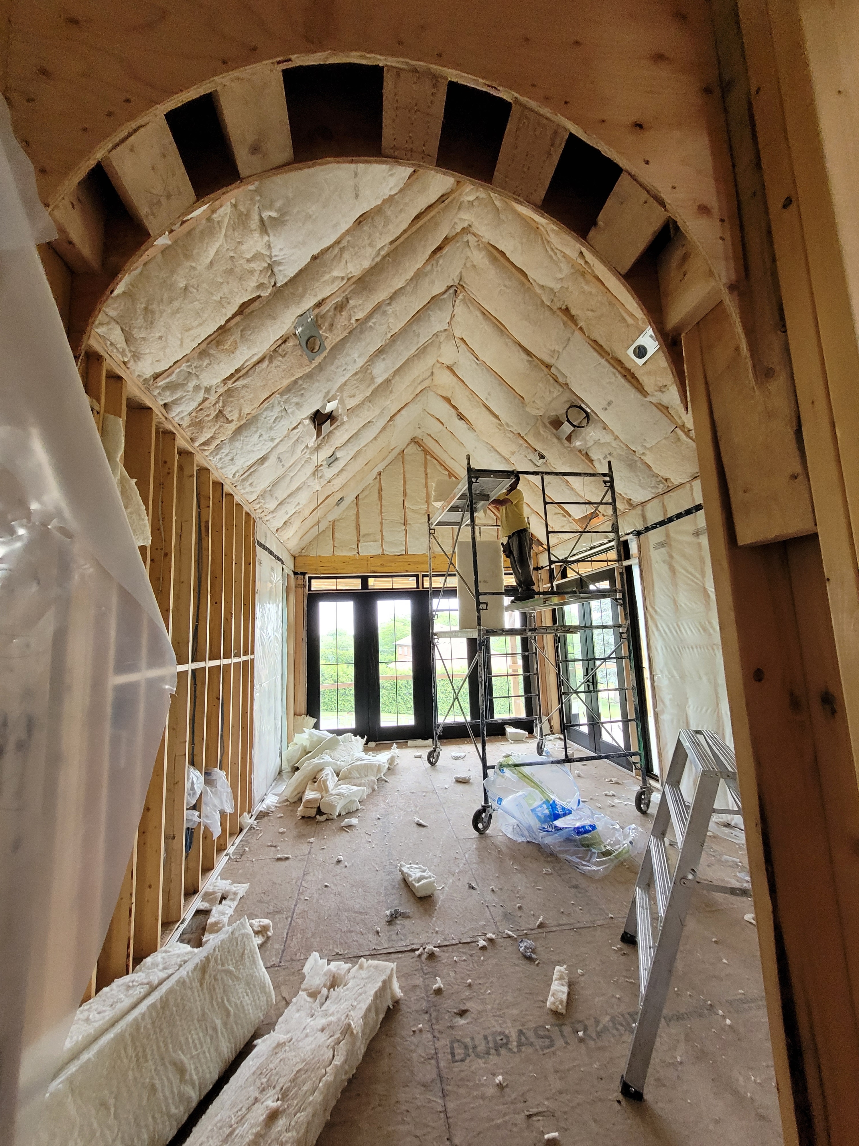 A house under construction with a work putting in insulation.