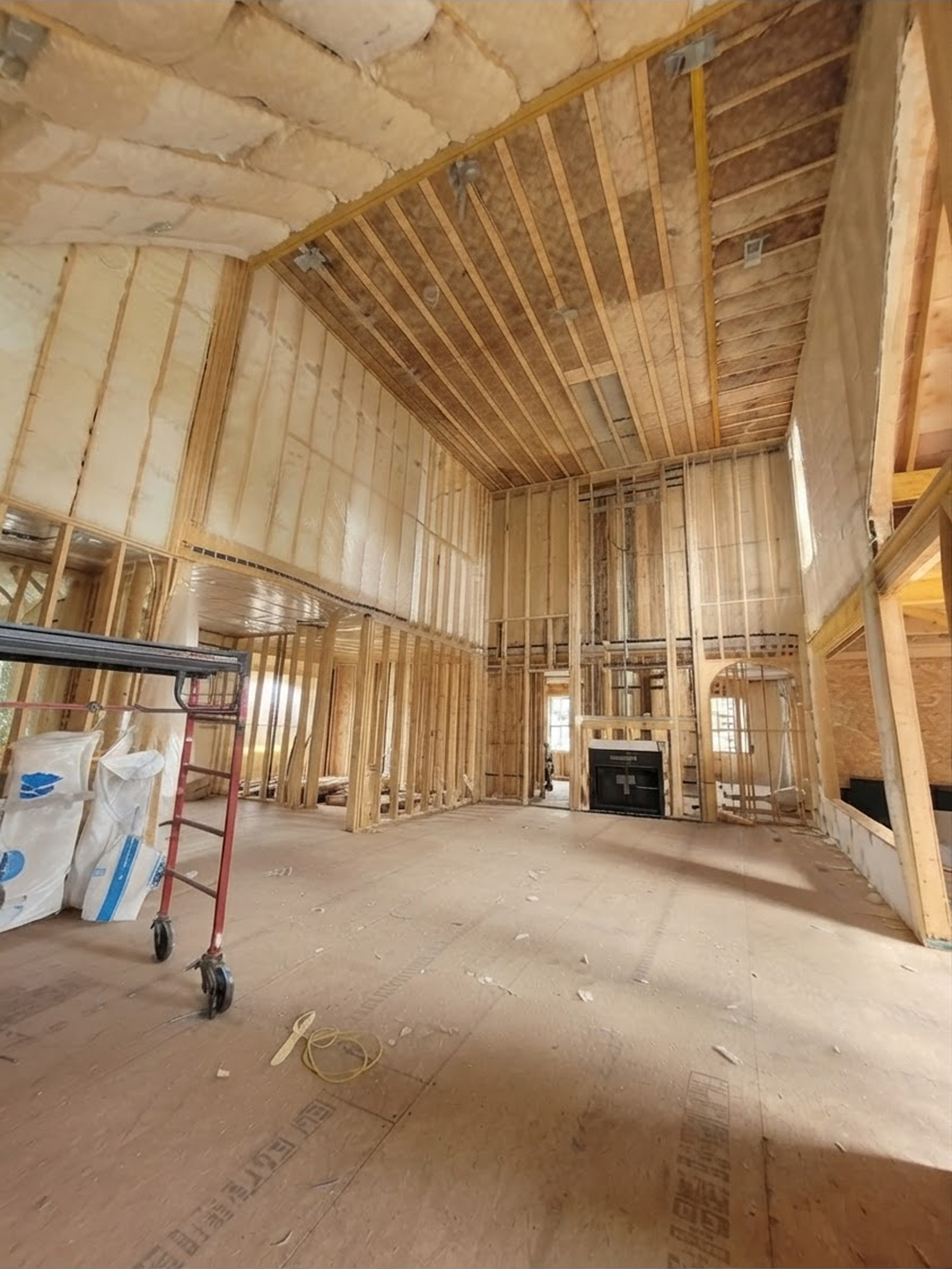 A large house under construction showing the interior walls and high ceilings with insulation panels installed.