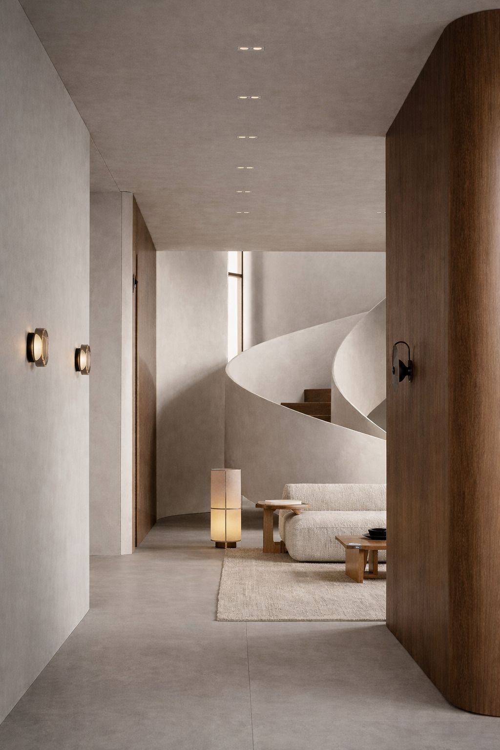 Minimalist beige living room corner with curved sofa, two cushions, a tall floor lamp, and a potted plant against a light wall panel.
