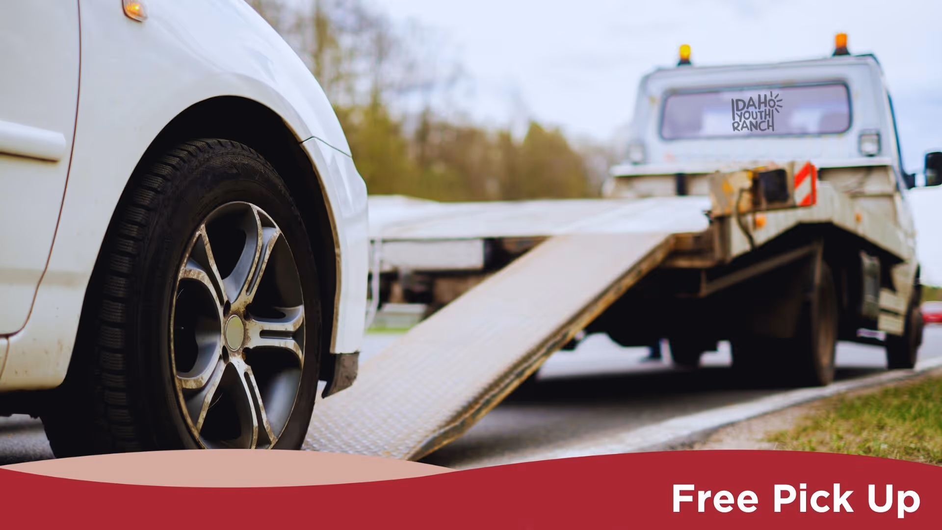 A white car being moved onto a tow truck with a ramp extended. The text at the bottom reads, "Free Pick Up."