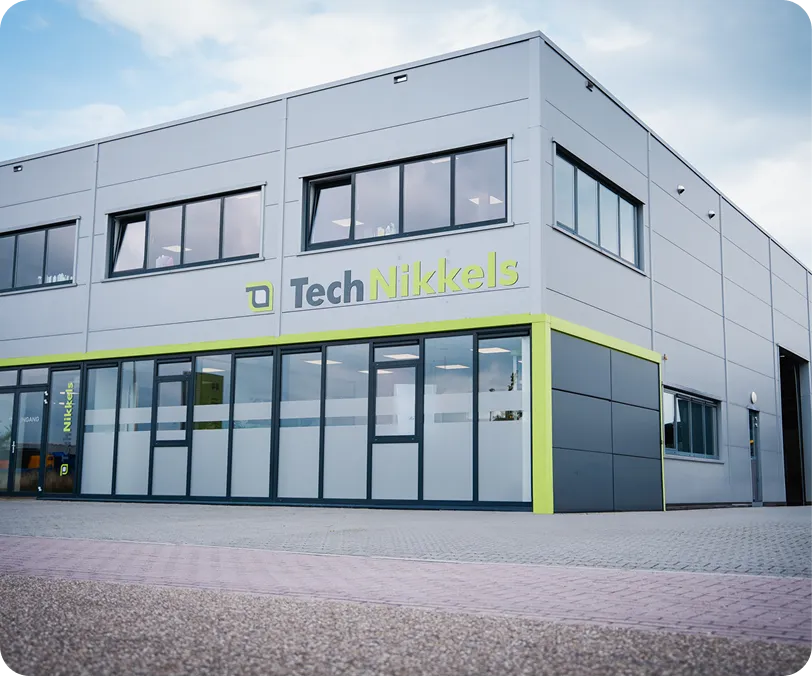 Bedrijfsgebouw met grijze en lichtgroene gevel en het logo van Tech Nikkels aan de bovenkant.