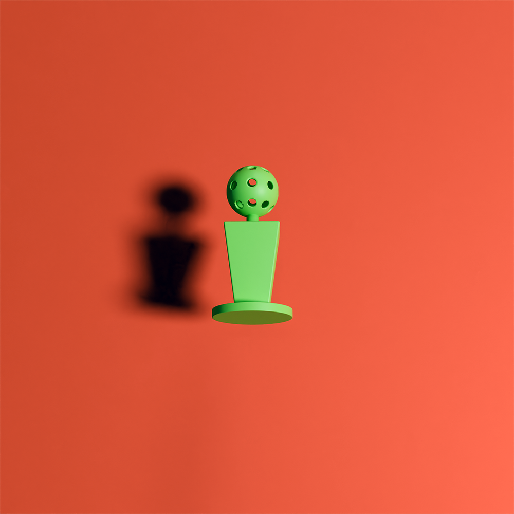 Green trophy with a perforated sphere on top casting a shadow on an orange background.