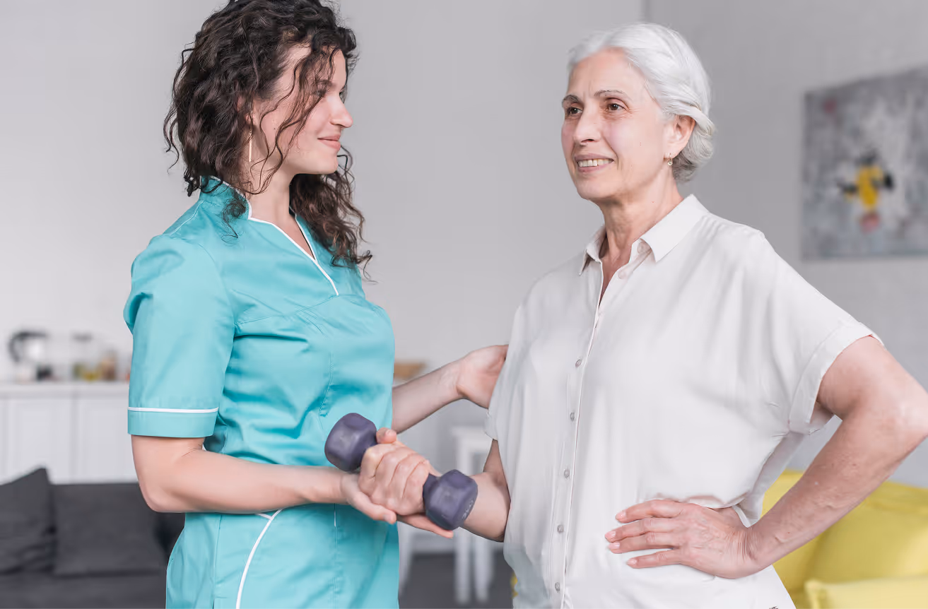 A healthcare professional in turquoise scrubs assisting an elderly woman holding a dumbbell during physical therapy.