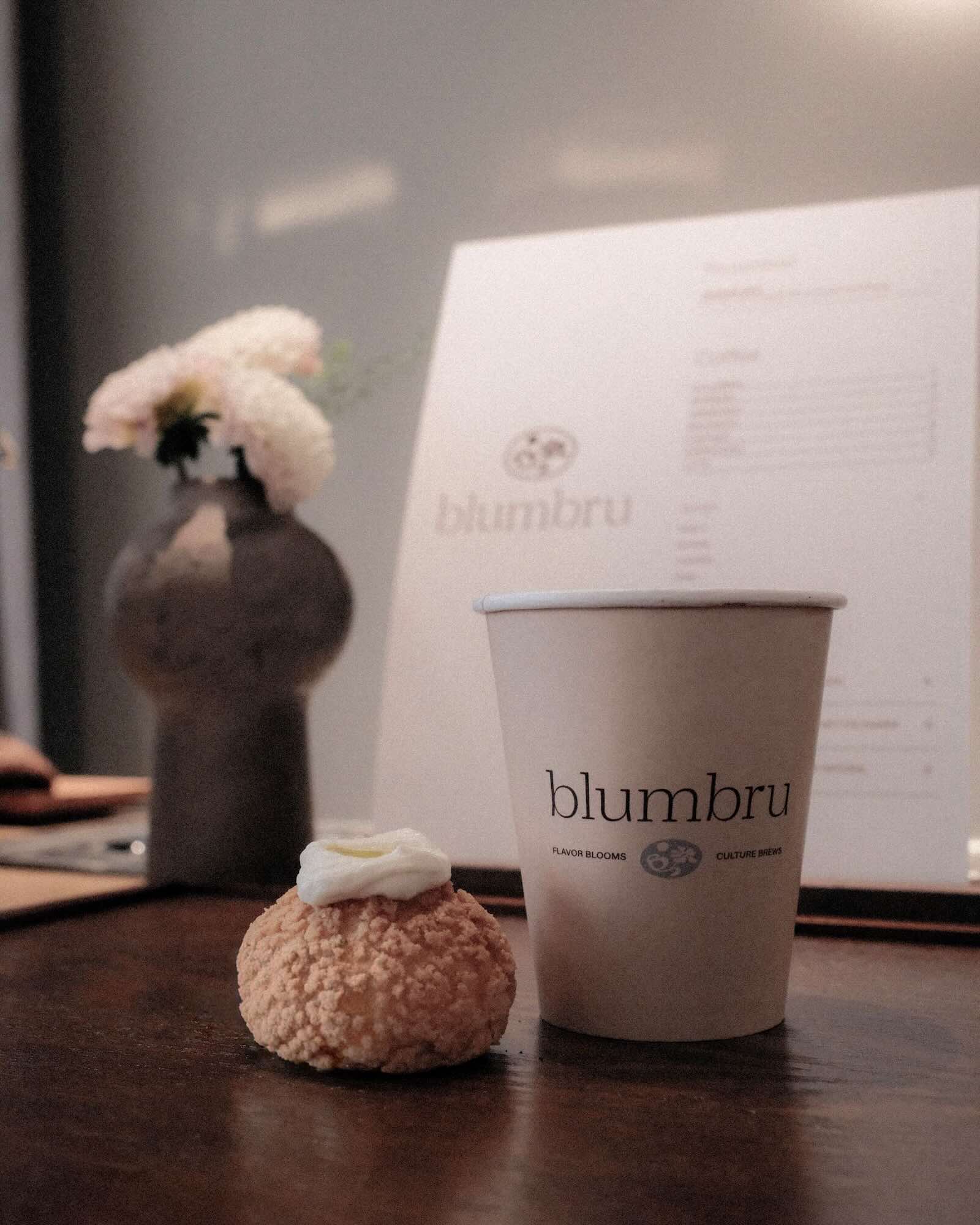 blumbru coffee cup next to luxury pastry.