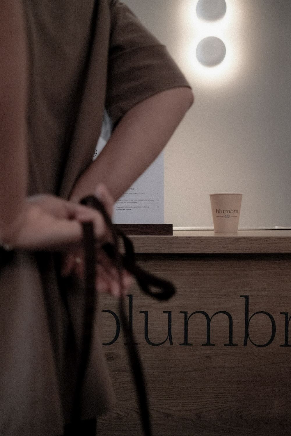 Barista tying up their apron in front of espresso bar.