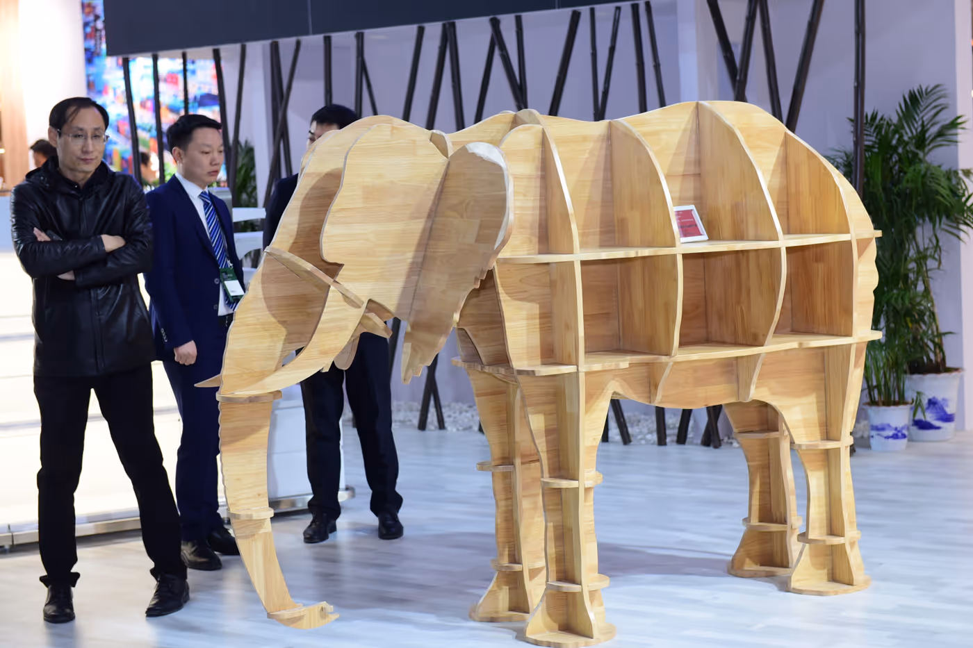 People gathered at an indoor trade show booth with shelves stocked with AERTAI branded boxes in a large exhibition hall.