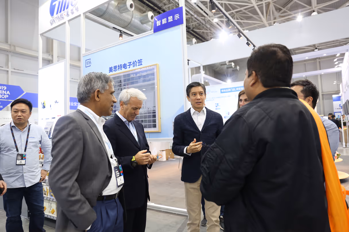 Industrial machinery with metal components displayed at a trade show with people in the background.