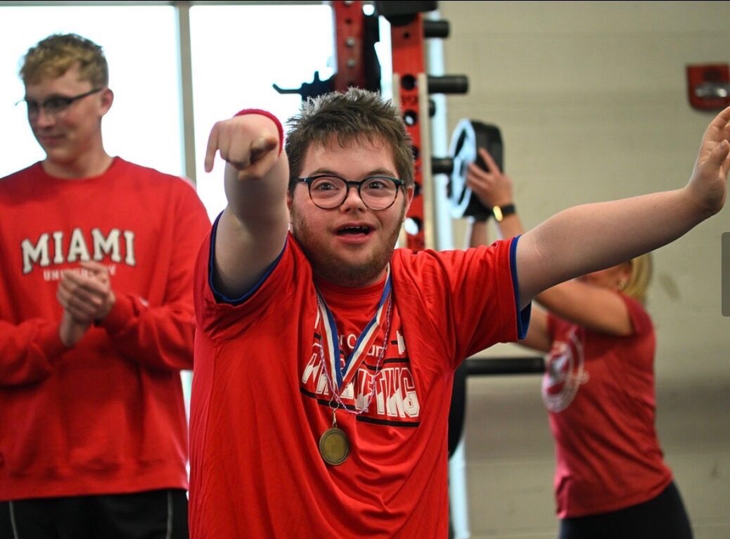 An athlete celebrating with a medal after a powerlifting competition