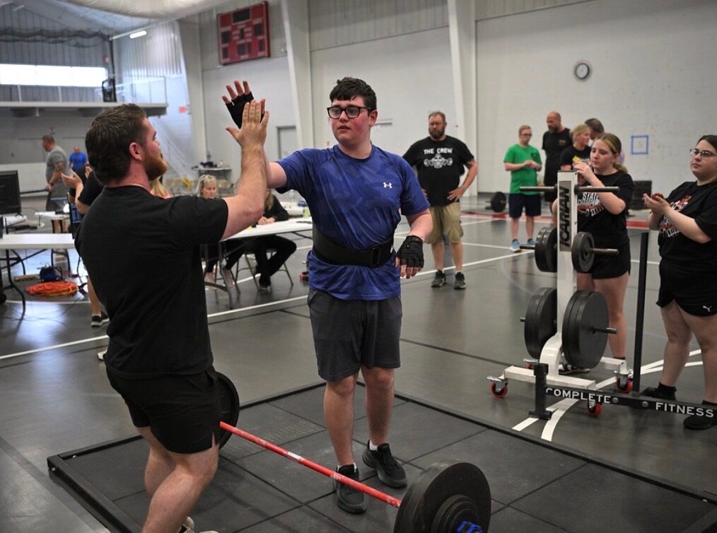 A coach high-fiving an athlete after a successful lift