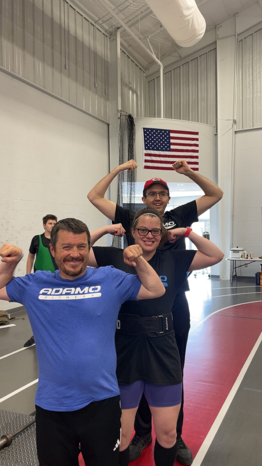 A coach and two athletes flexing together after training