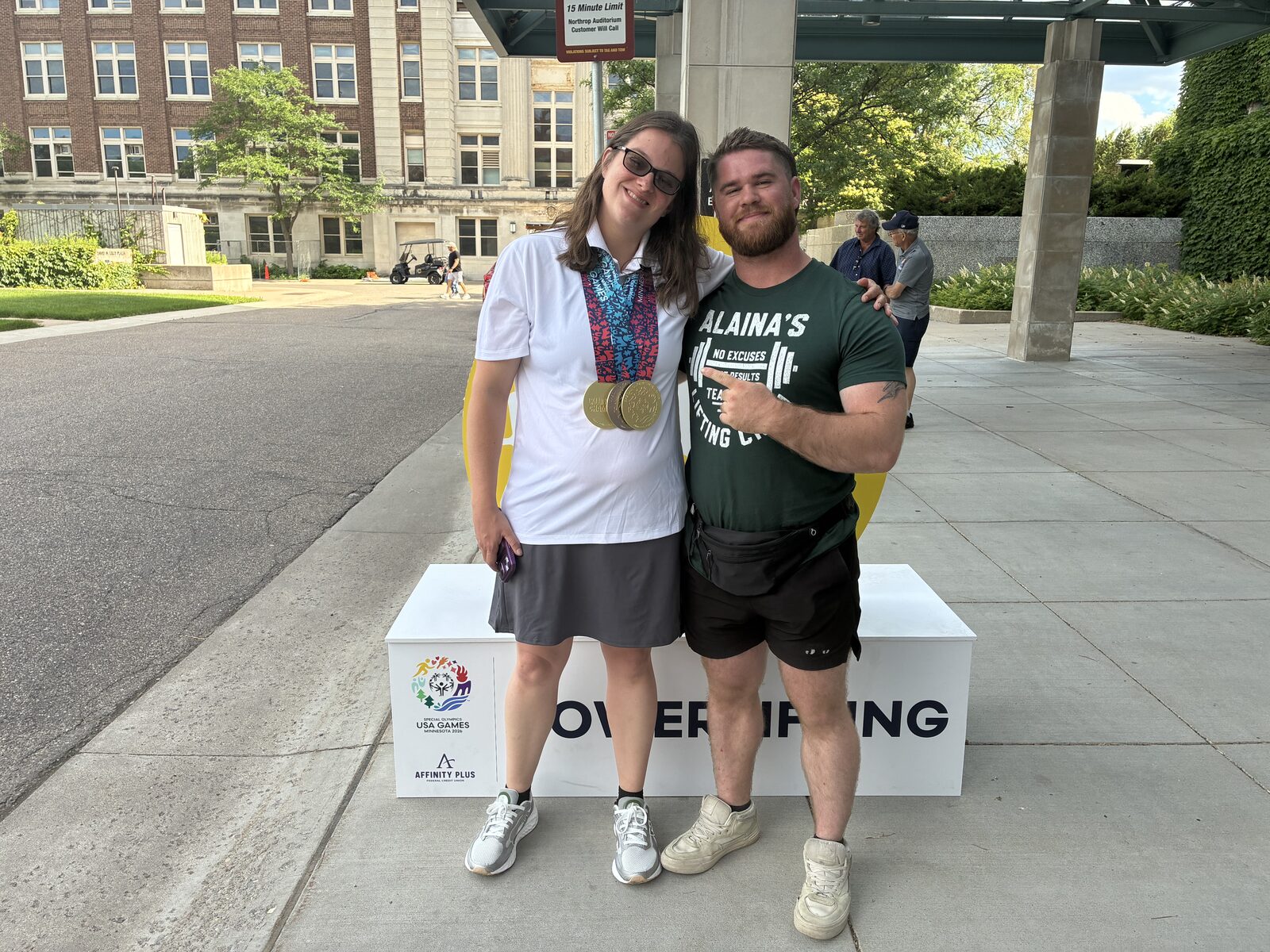 An athlete wearing gold medals with her coach at the Special Olympics USA Games
