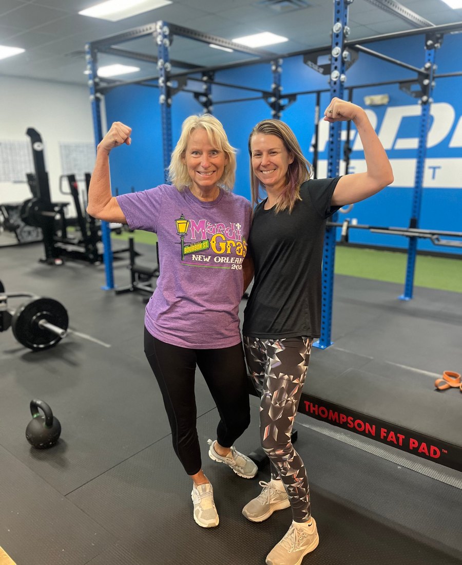 Two Adamo members flexing together in the gym after a session