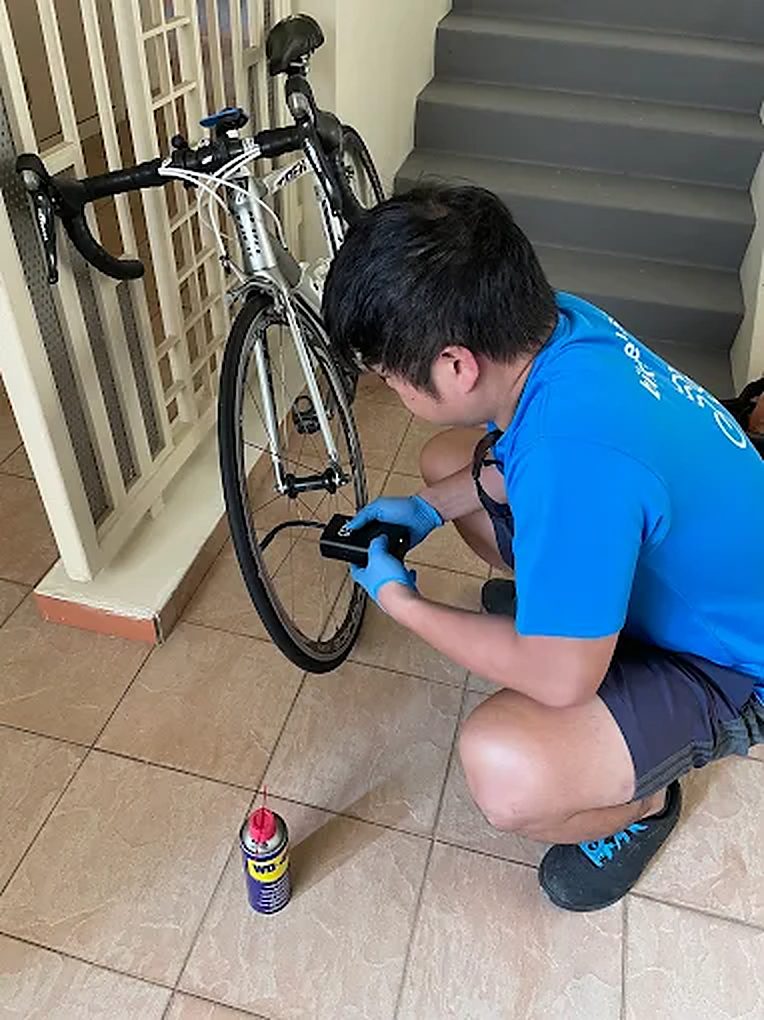 Bike Hero mechanic cleaning a road bike drivetrain at a house entrance