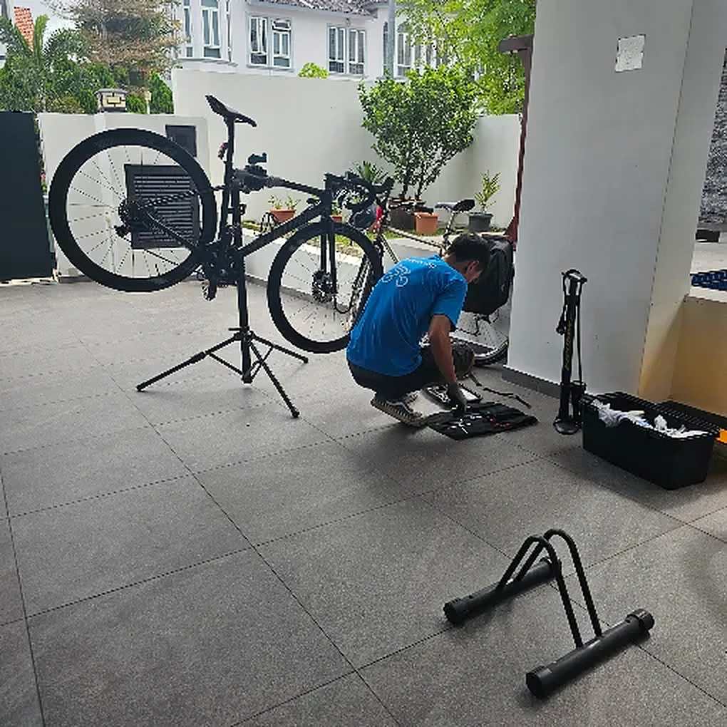Road bike on a work stand in a driveway while a Bike Hero mechanic services it