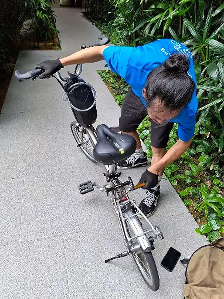 Bike Hero mechanic servicing a folding bike on a walkway outside a condo
