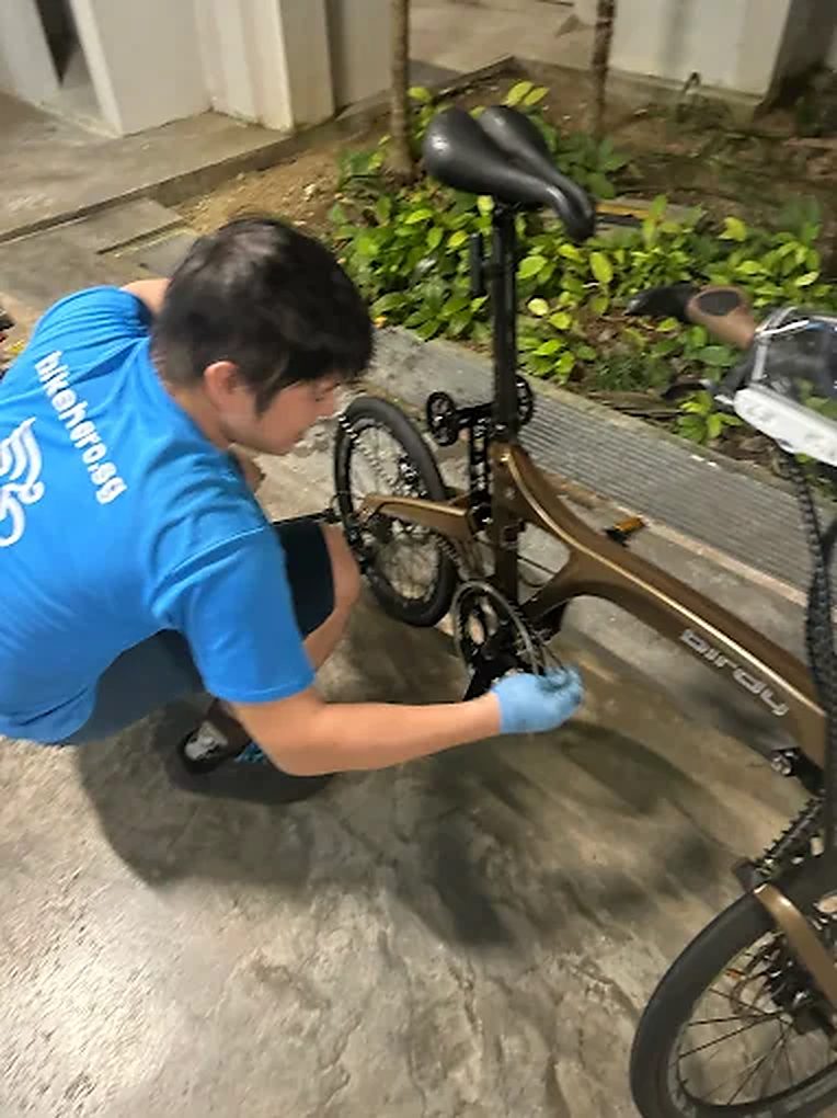 Bike Hero mechanic servicing a gold folding bike on site