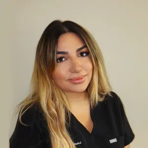 Portrait of a woman with long blonde hair wearing a black top, smiling against a plain background.
